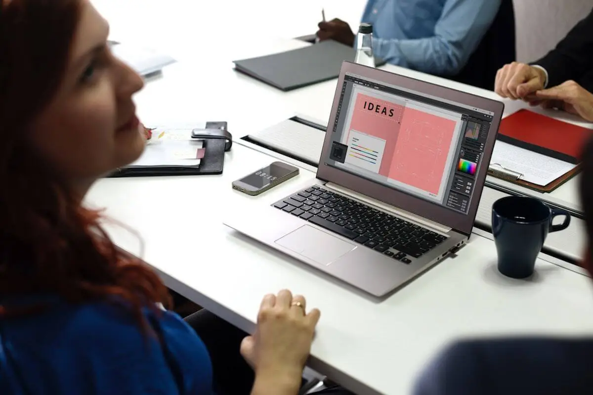 A group of people sitting around a table with a laptop.