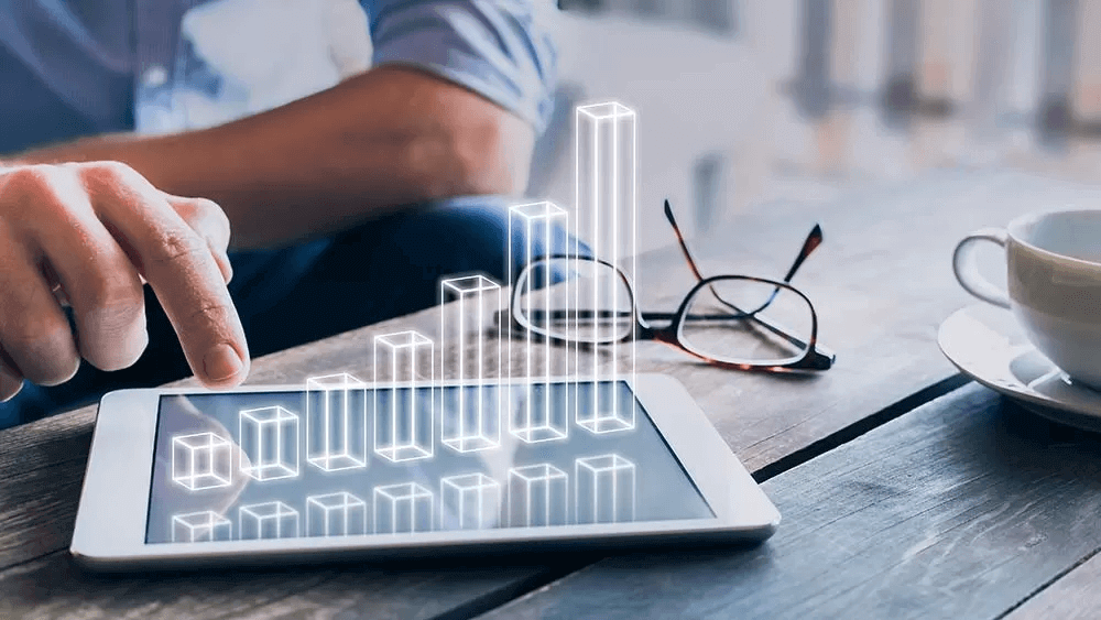 A man is pointing at a tablet with a graph on it.