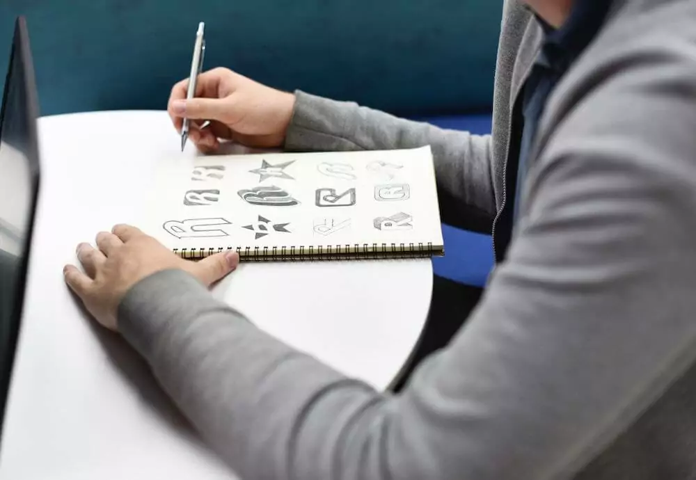 A man writing on a notebook with a pen.