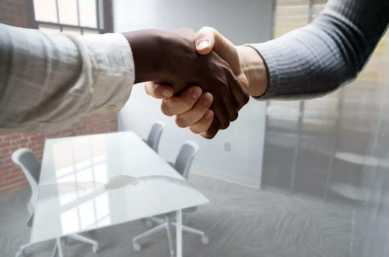 Two people shaking hands in an office.
