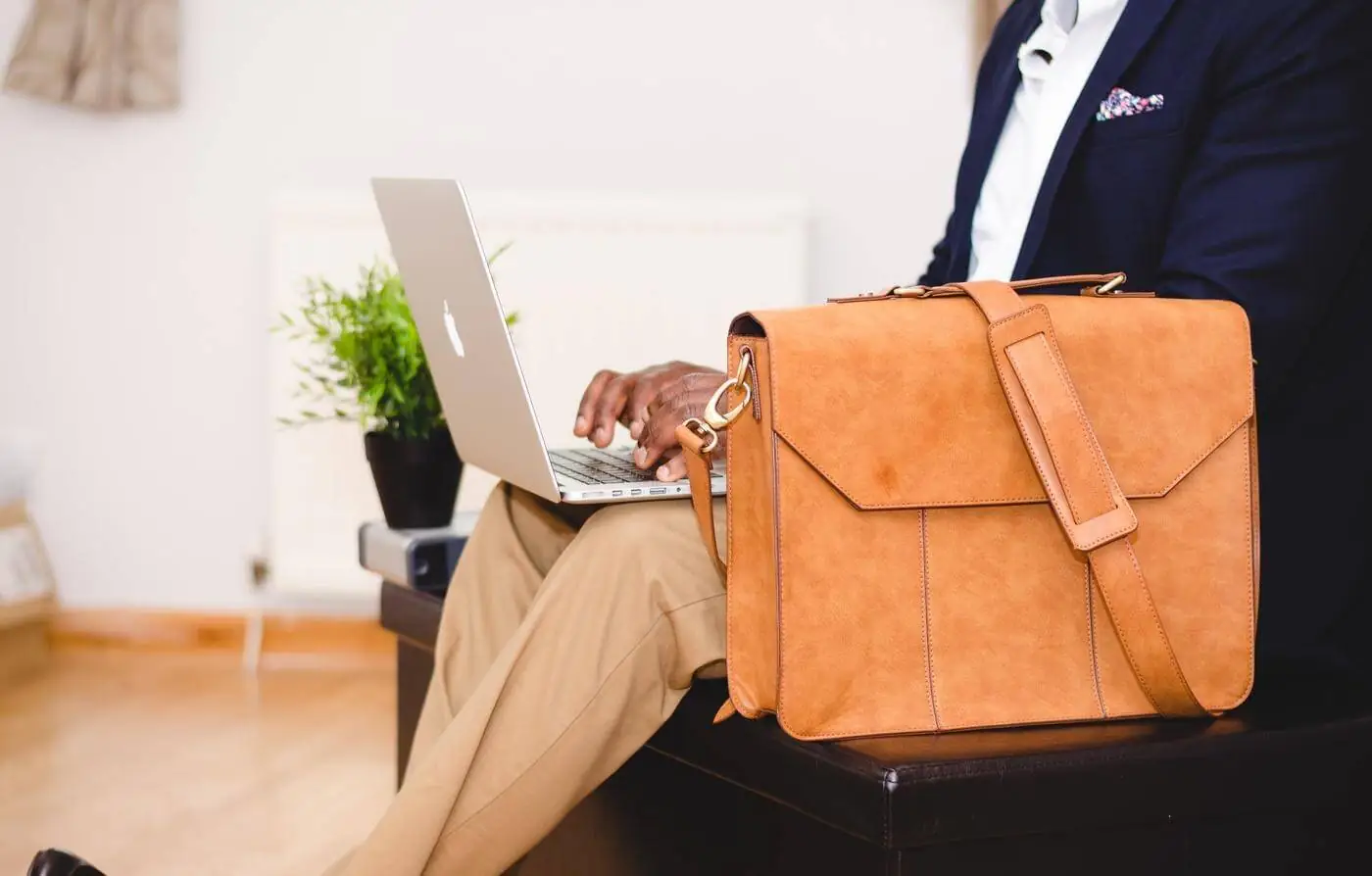 A man in a suit sitting on a couch with a briefcase.