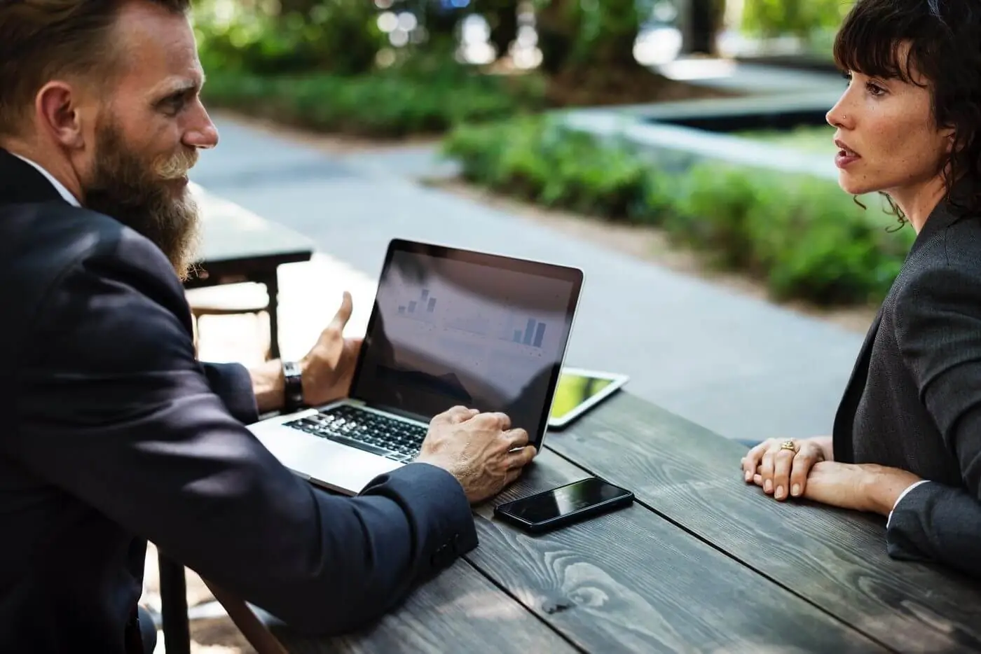 Two business people sitting at a table with laptops.