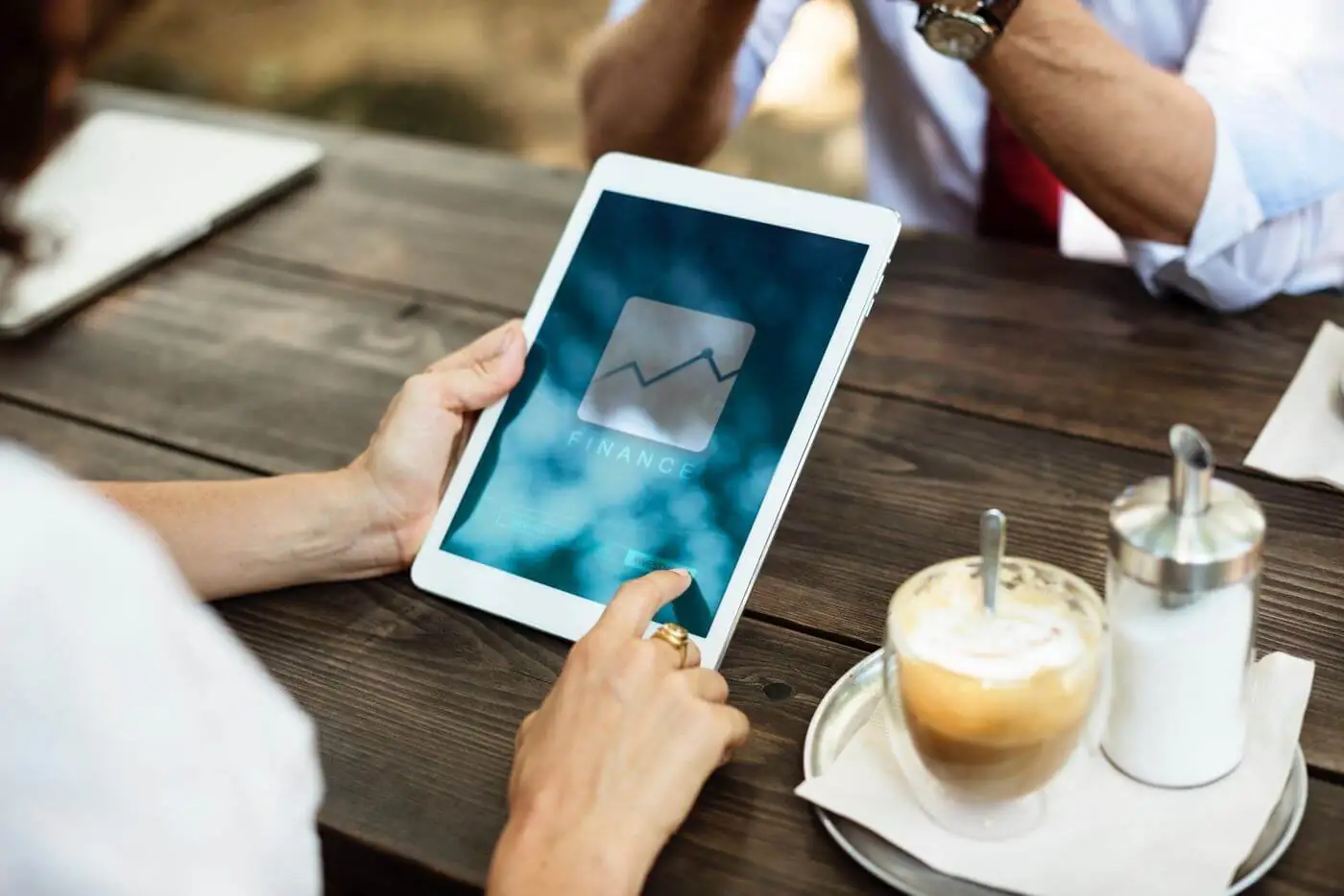 Two people sitting at a table with a tablet displaying a graph.