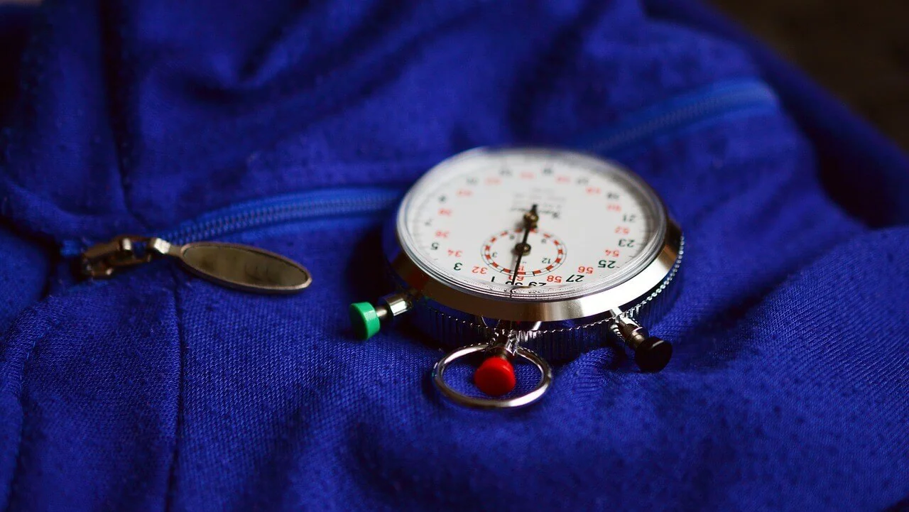 A stopwatch sitting on top of a blue jacket.