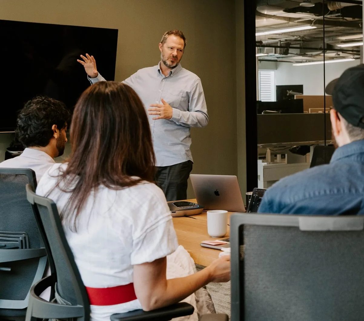 A man giving a presentation on digital marketing to a group of people in an office.